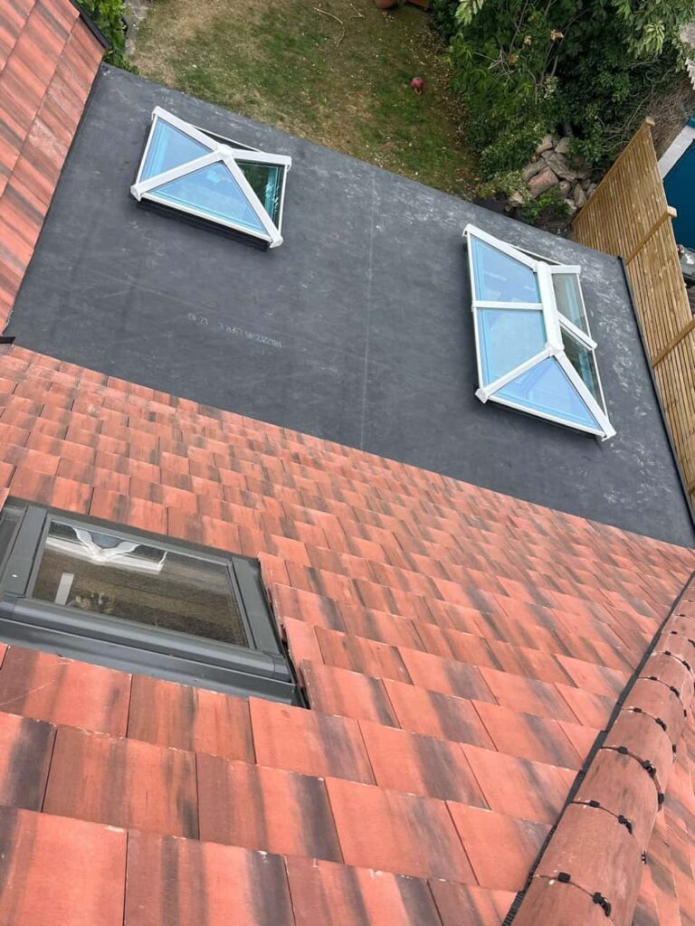 This is a photo taken from the roof ridge looking down a tiled pitched roof on to a flat roof. Works carried out by Brandon Roofing Repairs